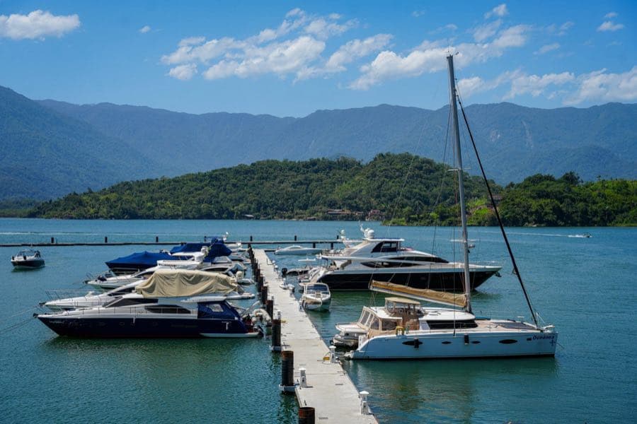 Píer flutuante com catamarã e lanchas atracadas, e a serra ao fundo