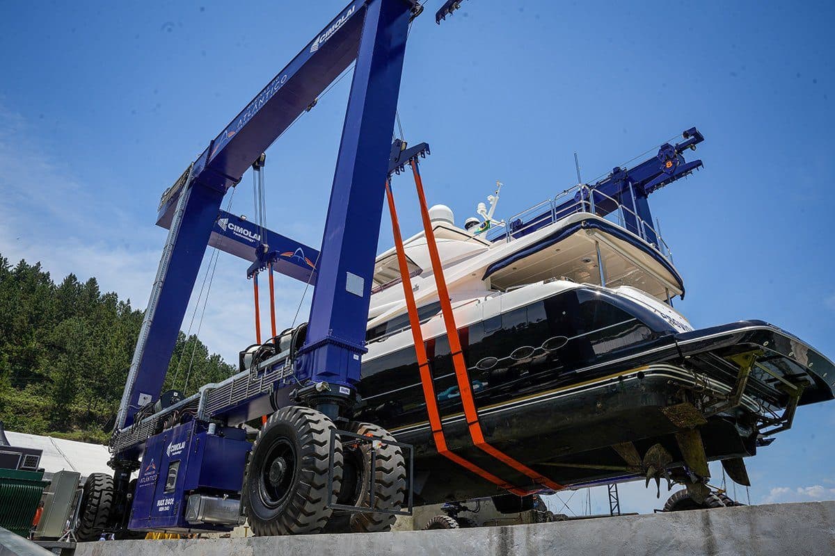 Travel lift transportando uma embarcação em terra, sobre as rodas